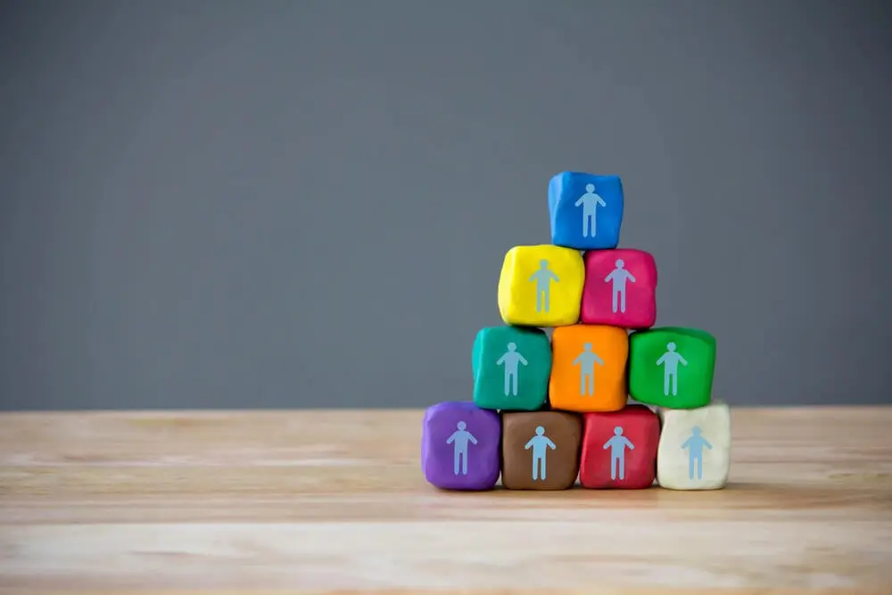 Colourful building blocks with a cartoon person on each. The building blocks have been put on top of one another to build a pyramid.
