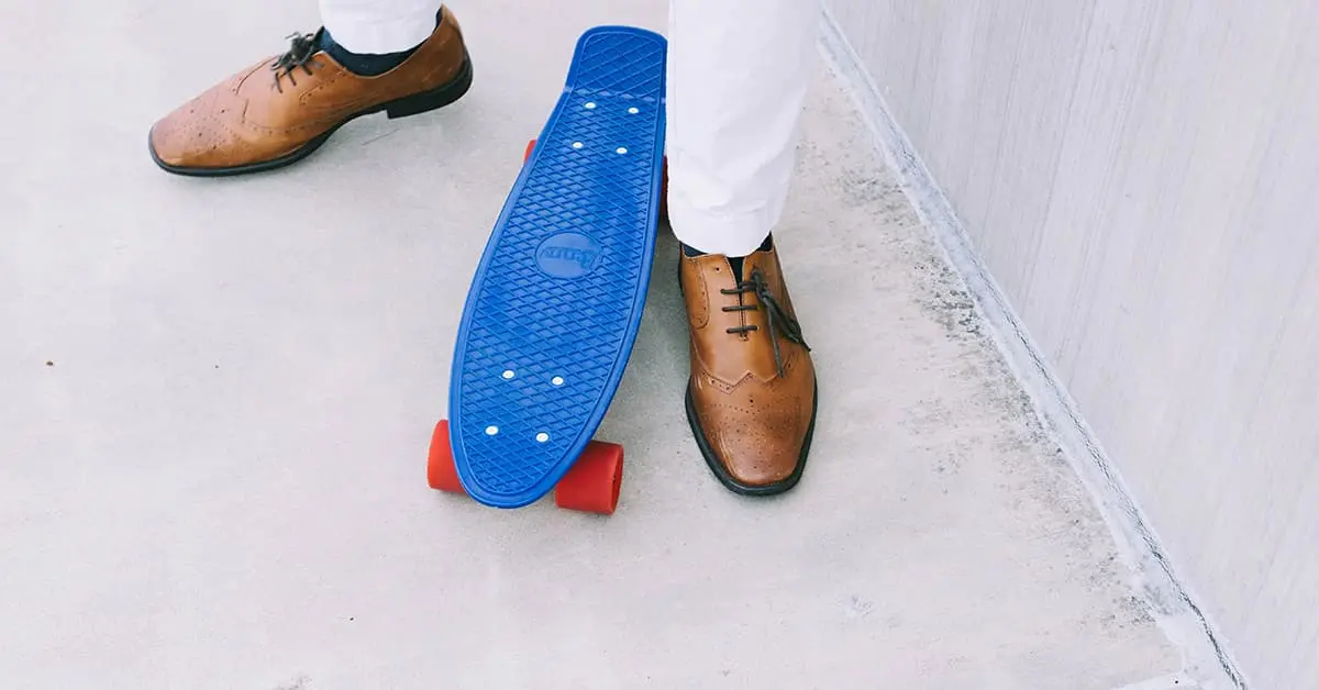 brown brogues placed next to small skateboard