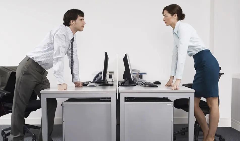 Man and woman staring at one another across a desk 