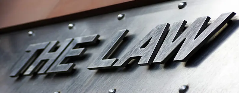 A dark steel sign with the words "the law" on it in metal capital letters that stand out from the sign.