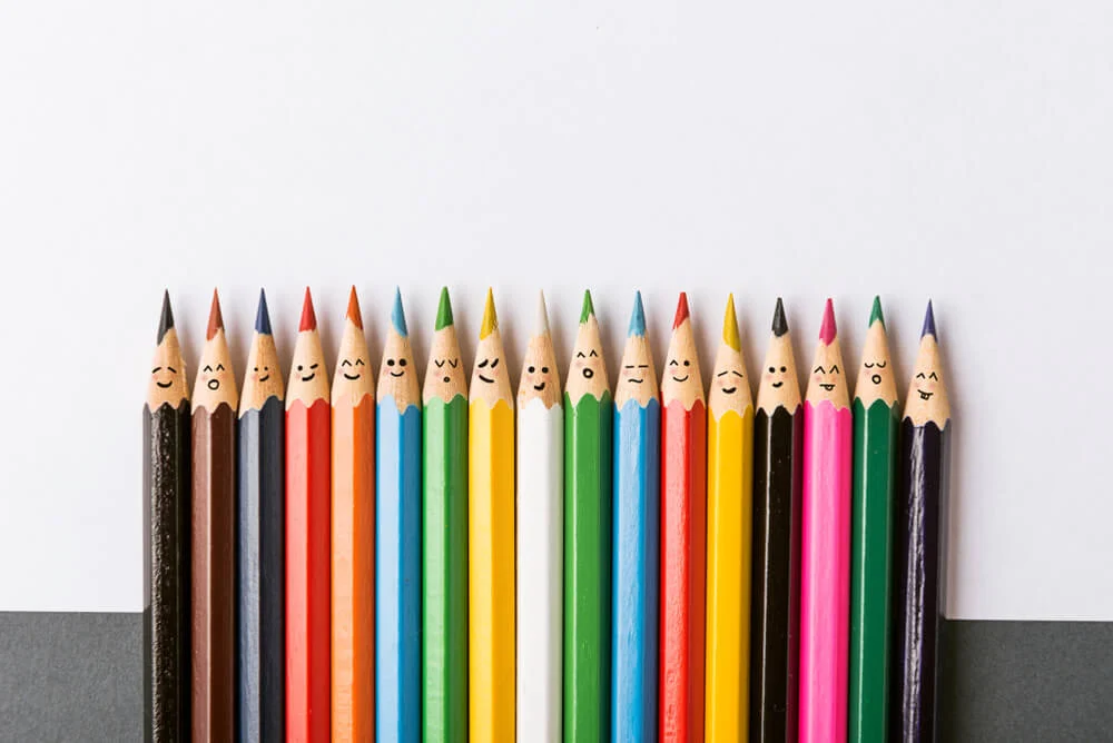 Row of multi-coloured pencils with different happy faces.