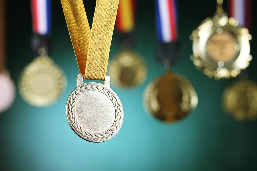 Several medals are dangling down. At the front there is a silver medal with a gold ribbon holding it up.