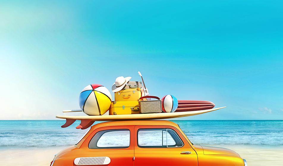A retro car is shown, driving parallel to a beach. A surfboard, suitcases and beach balls are strapped to the roof of the car, shown against the blue backdrop of the sky and sea.